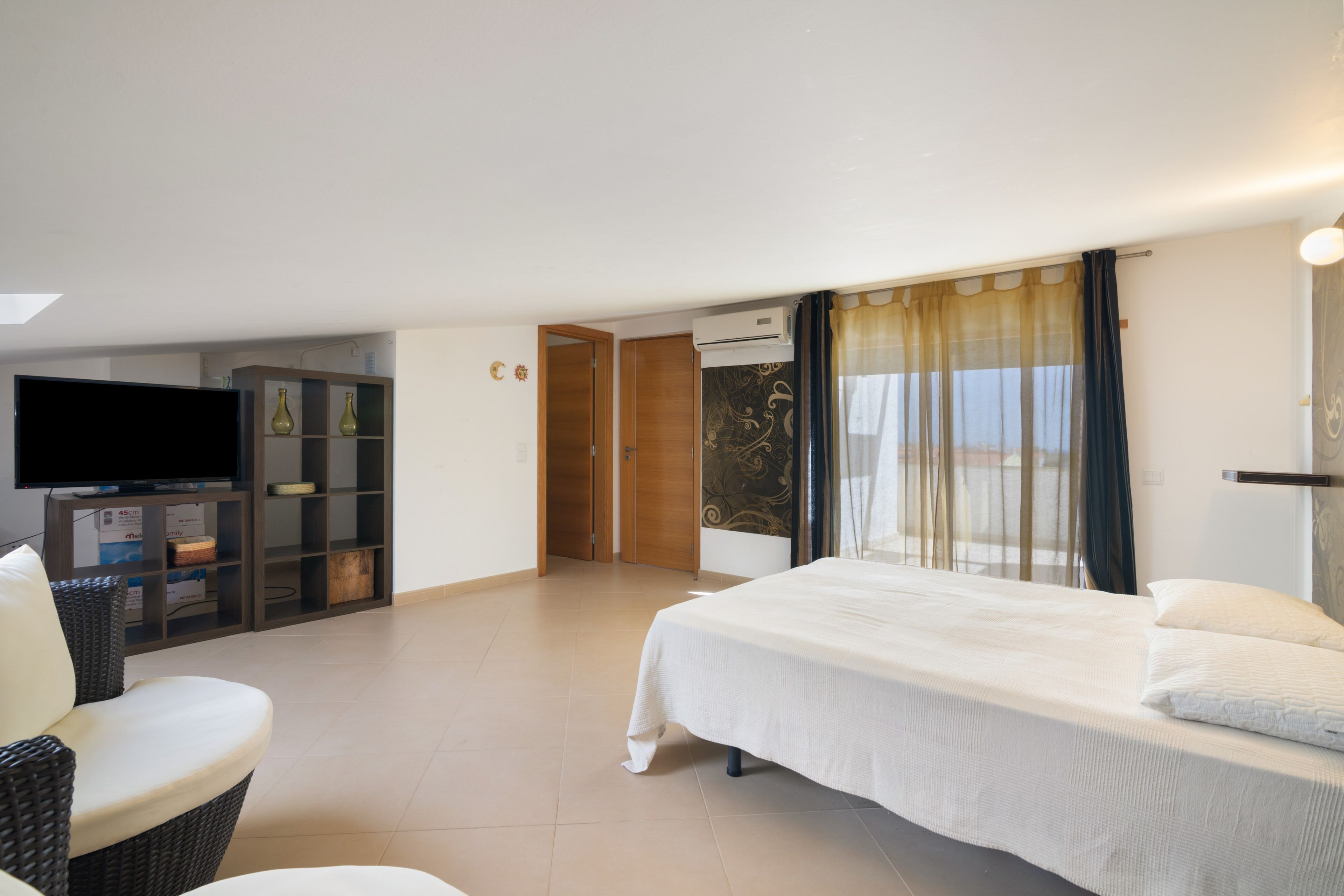 A hotel room with a bed, a television, a wardrobe, and a seating area.