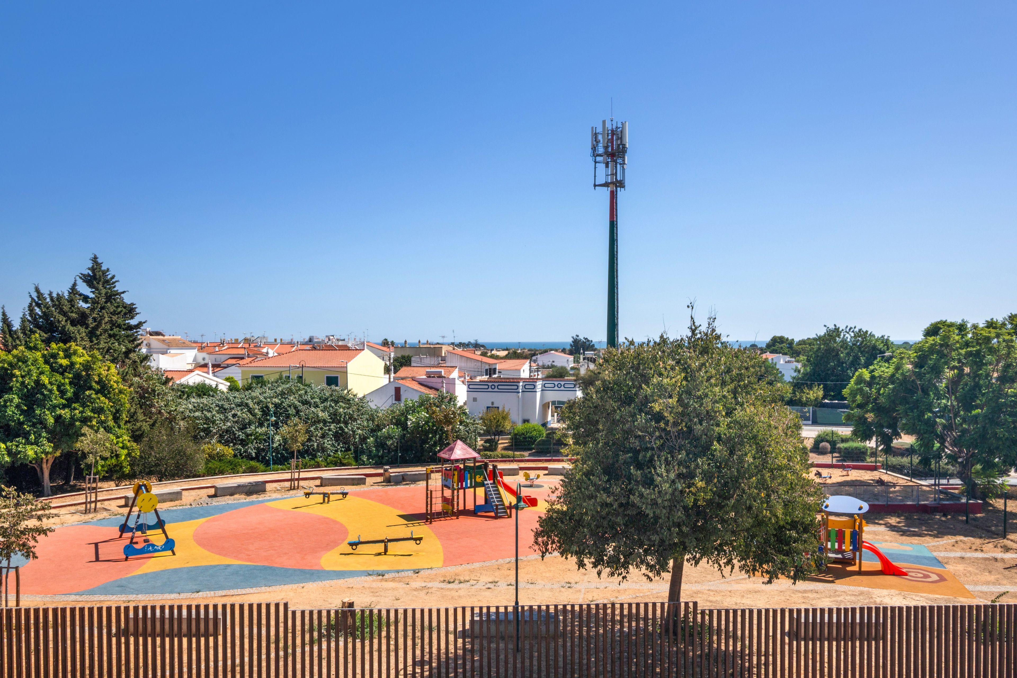 A playground with colorful equipment and a tall communication tower in the background.