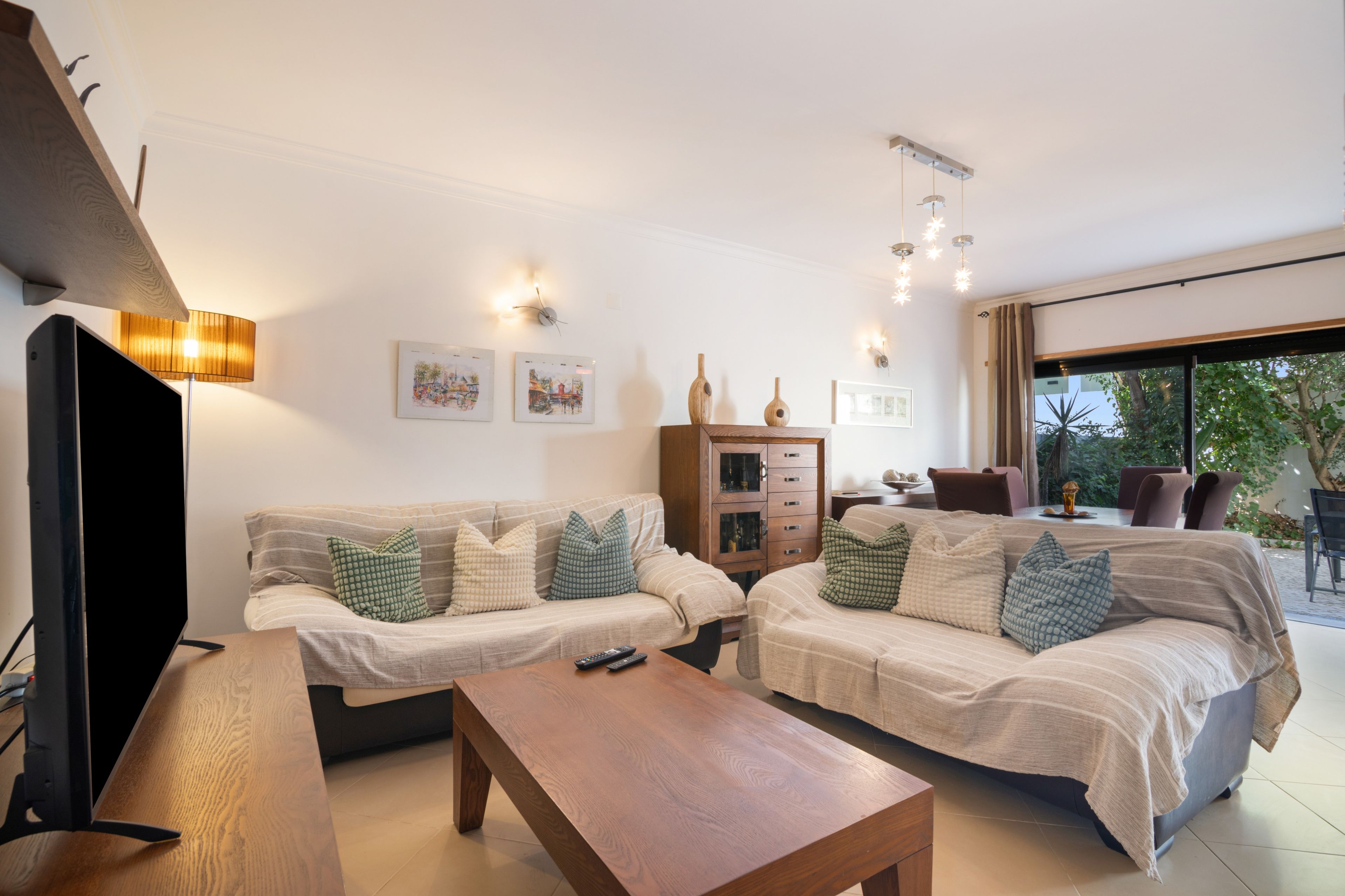 Ein modernes Wohnzimmer mit einer Sofagarnitur, einem Couchtisch und einem Fernseher.