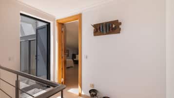 Un pasillo con una escalera, una puerta de madera y una obra de arte colgada en la pared.