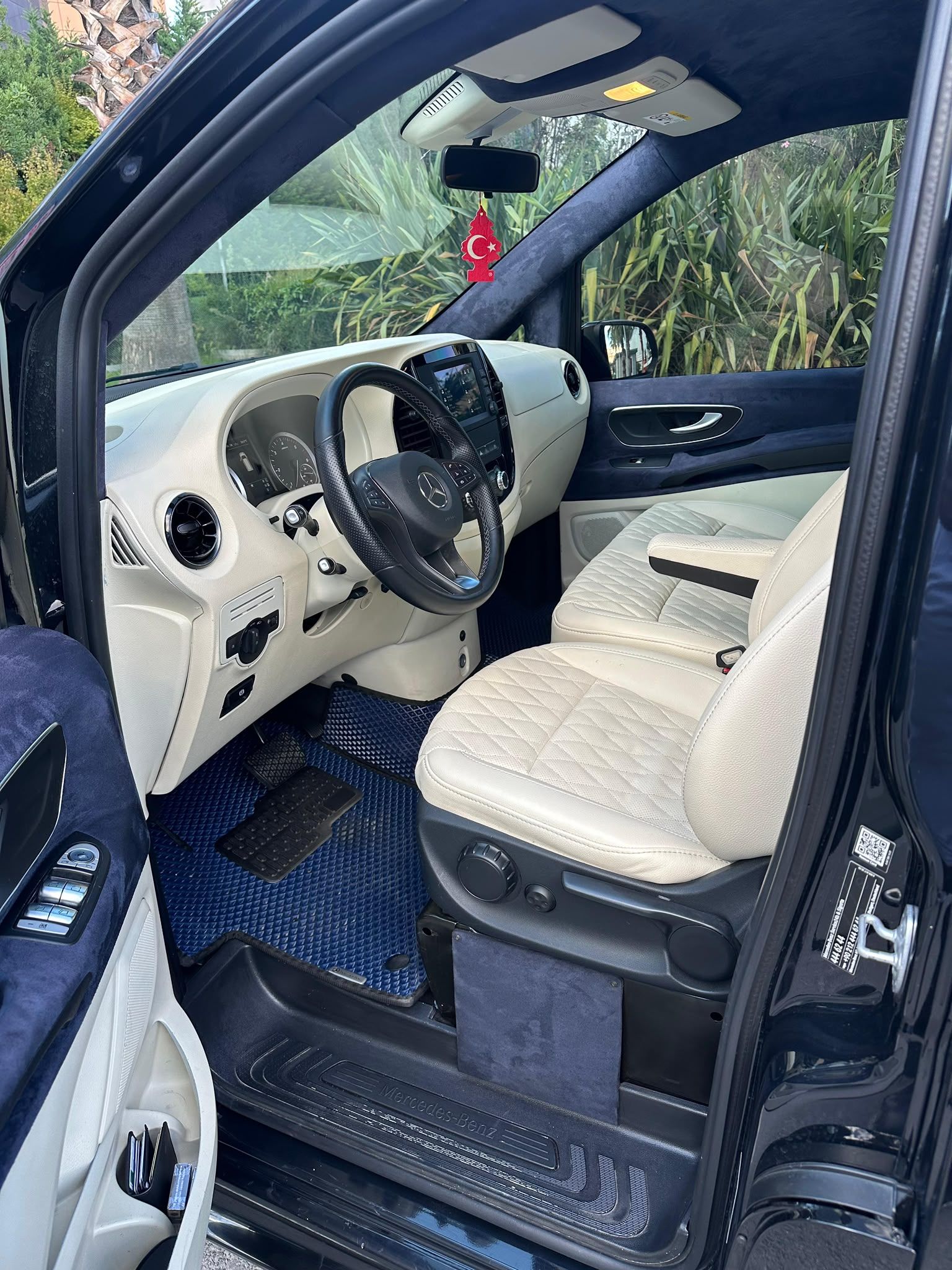 L'intérieur d'une voiture avec un volant, un tableau de bord et des sièges de couleur beige.