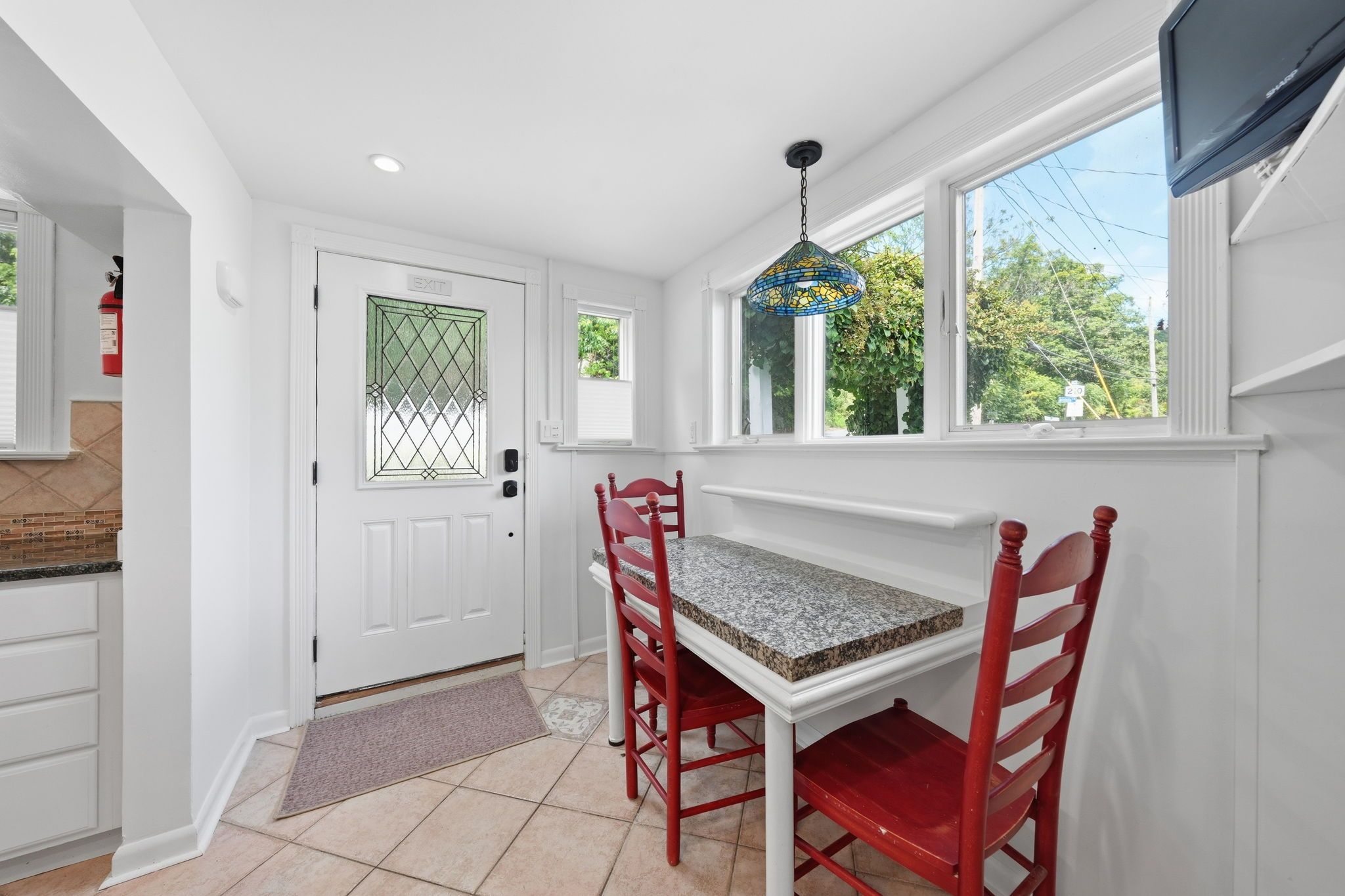 A kitchen with a dining table, chairs, a window, and a door.