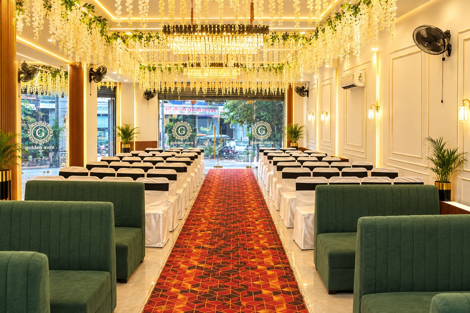 Habitación de hotel con alfombra estampada, sillones tapizados en verde y una lámpara de araña.