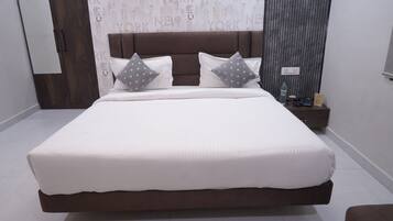 A large bed with a brown headboard, white bedding, and two pillows with gray polka dots.