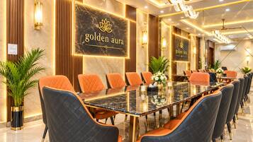 Un salón de conferencias con una larga mesa, varias sillas y una pared con el texto 'golden aura'.