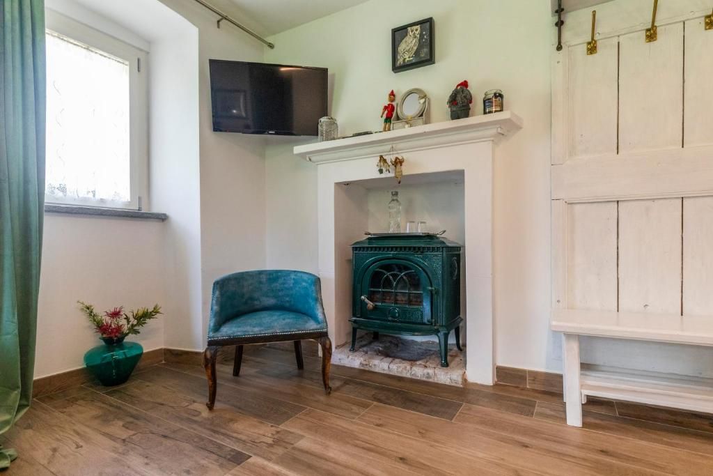 Una habitación con chimenea, un televisor montado sobre ella, un sillón azul y suelo de madera.