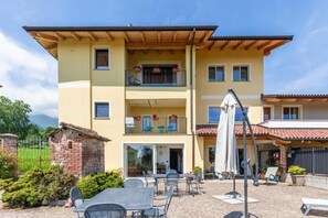 Un immeuble à plusieurs étages doté d’un patio aménagé avec des espaces de détente en plein air et des parasols.