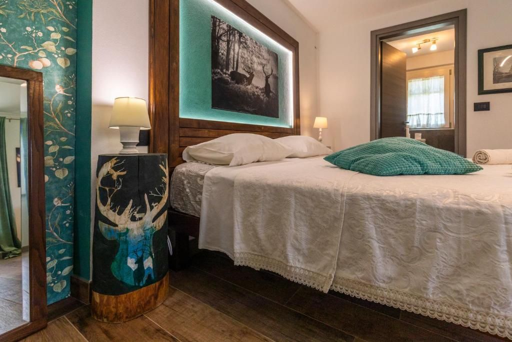 Un dormitorio con una cama, una mesita de noche, una lámpara de pared y un cuadro enmarcado sobre la cama.