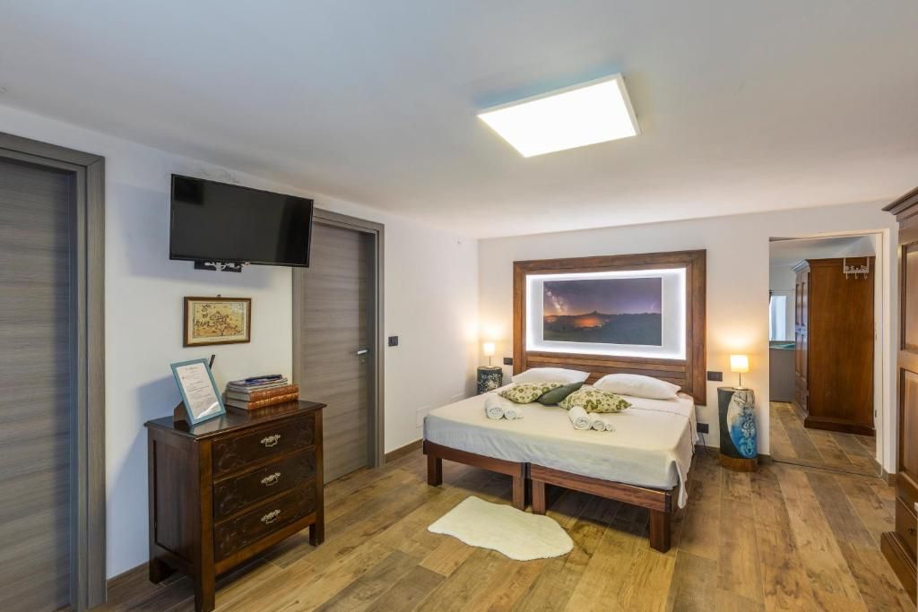 Un dormitorio con una cama, lámparas de noche, un televisor de pantalla plana, un aparador y un cuadro en la pared.