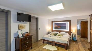 Un dormitorio con una cama, lámparas de noche, un televisor de pantalla plana, un aparador y un cuadro en la pared.