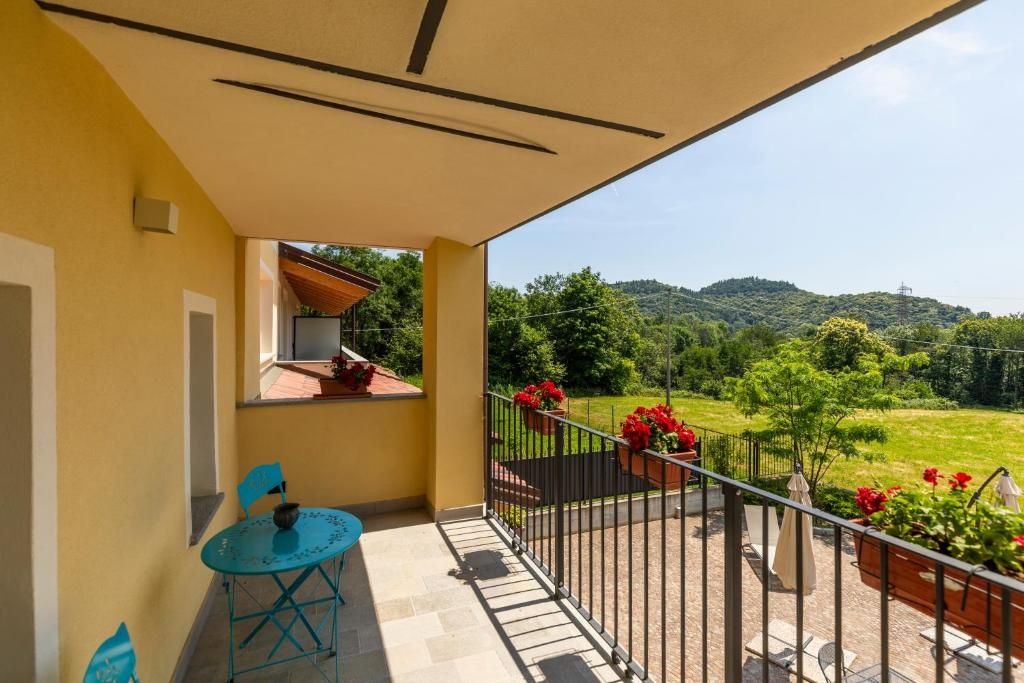 Een balkon met een tafel en stoelen, een uitzicht op een groen landschap en een hekwerk.