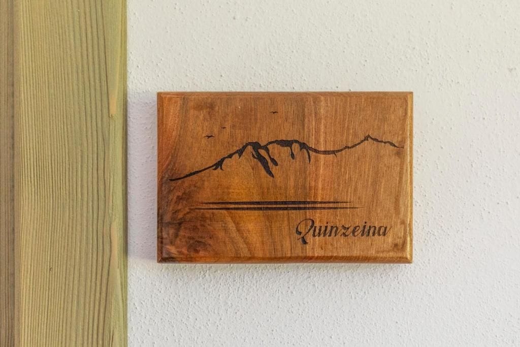 A wooden plaque with a mountain silhouette and the name 'Quinceña' engraved on it.