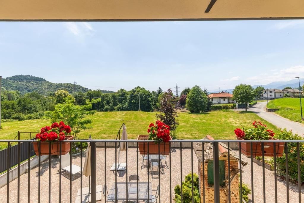 Un balcón con mobiliario exterior, vistas a un paisaje verde y una carretera a lo lejos.