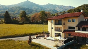 Un bâtiment à deux étages, doté d’un toit recouvert de tuiles rouges, d’un balcon et offrant une vue sur une chaîne de montagnes.