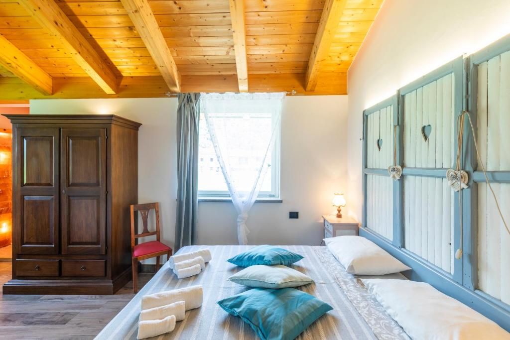 Une chambre avec un plafond en bois, une grande armoire, un lit avec des oreillers et une fenêtre avec des rideaux.