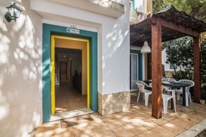 A building entrance with a sign 'LOTE 3-B', a covered outdoor seating area with tables and chairs, and a tiled patio. - Apartment 'Real Village' with Private Terrace, Wi-Fi and Air Conditioning (Altura)