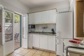A kitchen with white cabinets, a built-in microwave, and a refrigerator.