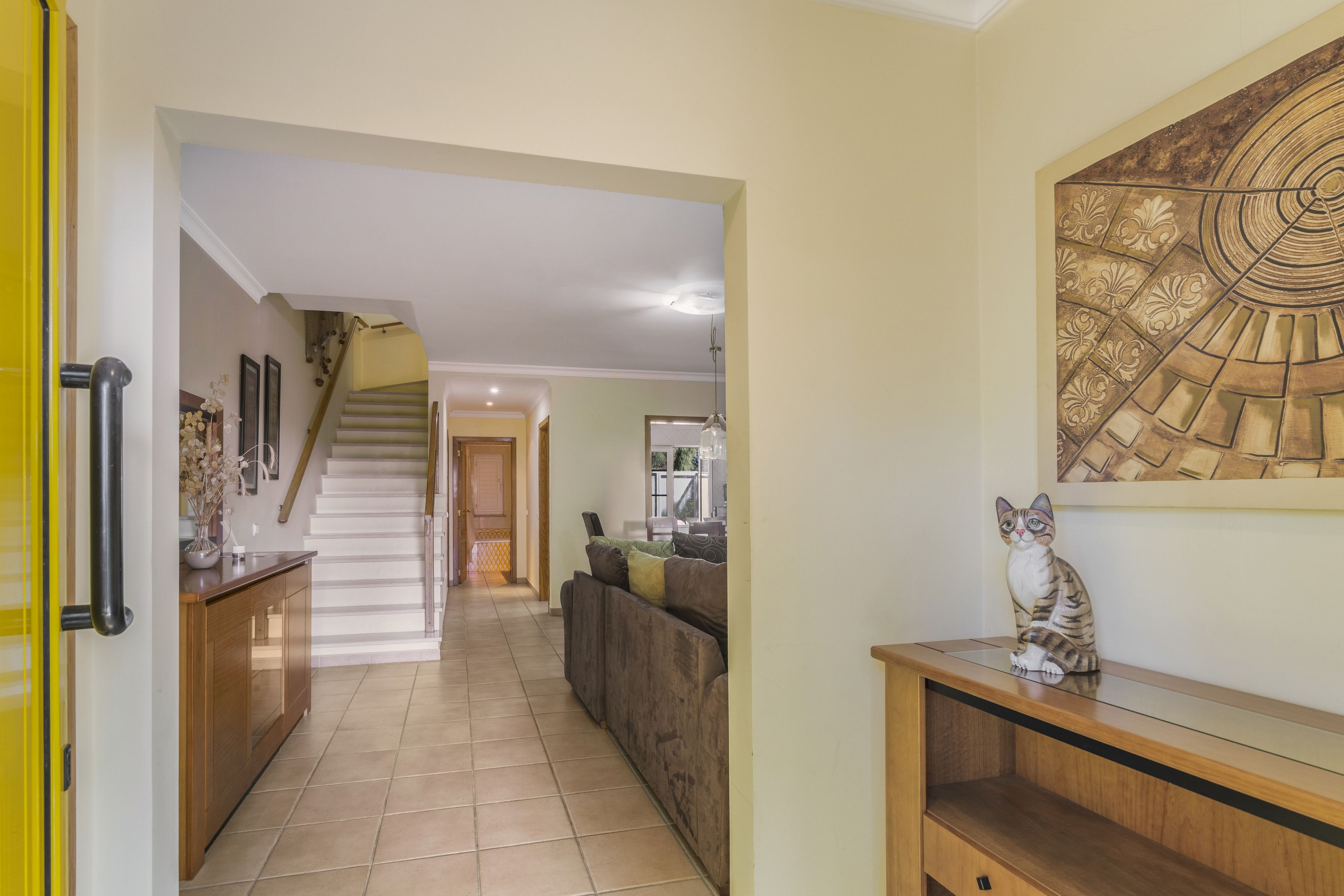 A hallway with a staircase leading to another room, a sofa, and a decorative wall piece.