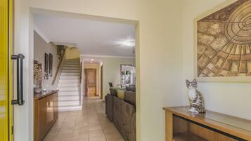 A hallway with a staircase leading to another room, a sofa, and a decorative wall piece.