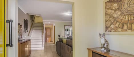 A hallway with a staircase leading to another room, a sofa, and a decorative wall piece.