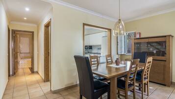 A dining area with a wooden table, chairs, and a hanging light fixture.