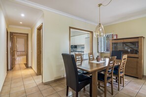 A dining area with a wooden table, chairs, and a hanging light fixture. - Apartment 'Real Village' with Private Terrace, Wi-Fi and Air Conditioning (Altura)