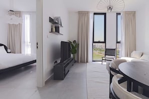 Een moderne hotelkamer met een bed, een zithoek met een tafel, een televisie en een balkon met uitzicht.