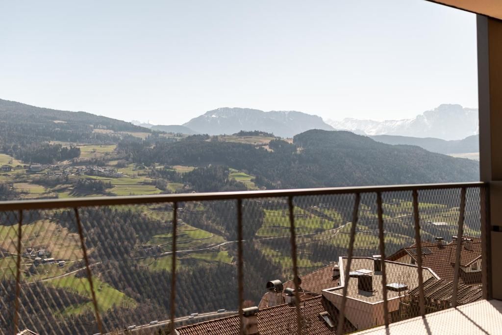 A balcony with a view of a valley and distant mountains.