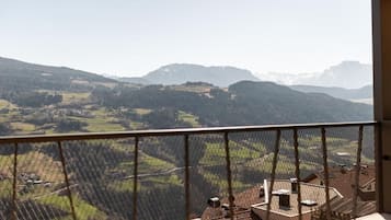 A balcony with a view of a valley and distant mountains.