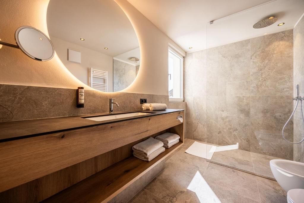 Une salle de bain moderne avec un meuble-lavabo en bois, un grand miroir et un espace douche.
