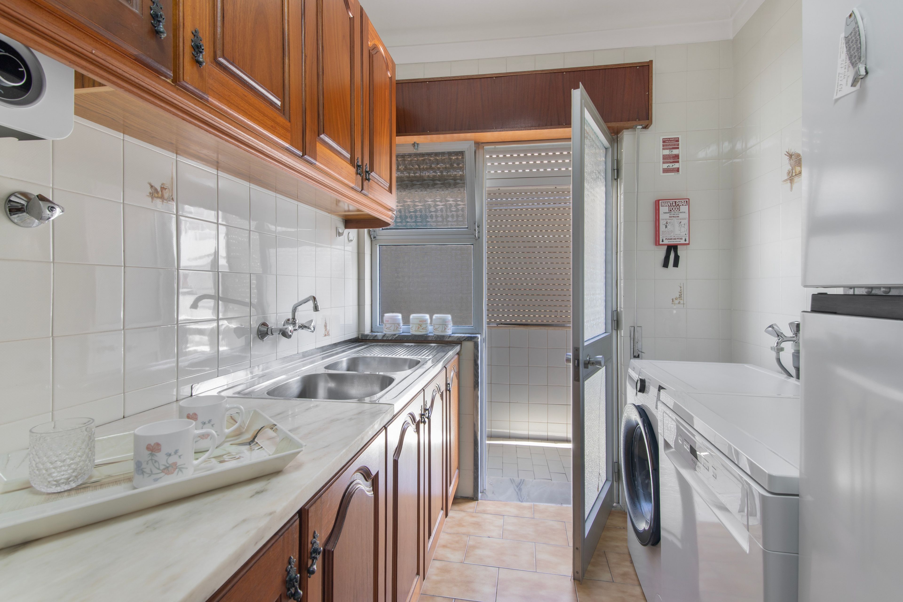 Een moderne keuken met houten kastjes, een dubbele spoelbak, een inbouwoven en een wasmachine.