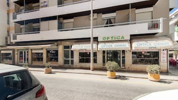 Un edificio de varios pisos con locales comerciales, incluyendo una óptica llamada 'OPTICA OEIRAS' y una tienda de redes sociales llamada 'SOCIAL ALFA'.