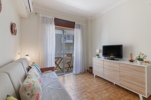 A living room with a sofa, a television on a wooden cabinet, and a sliding glass door leading to a balcony. - Apartment 'Ocean Stay Ap' with Balcony, Wi-Fi and Air Conditioning (Monte Gordo)