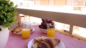Ein Balkon mit Frühstücksangeboten, darunter Croissants, Trauben und Orangensaft.