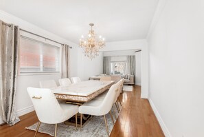 Ein Esszimmer mit einem Marmortisch, weiß gepolsterten Stühlen und einer Kristallleuchter.