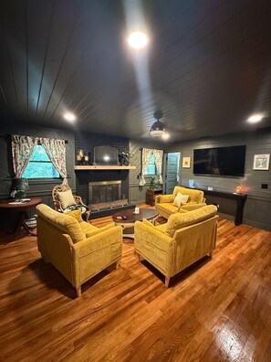 A living room with a fireplace, two yellow armchairs, a coffee table, and a flat-screen TV mounted on the wall. - Highlands Mountain Hideaway. Views, Fireplace & Minutes to Downtown. (Highlands)