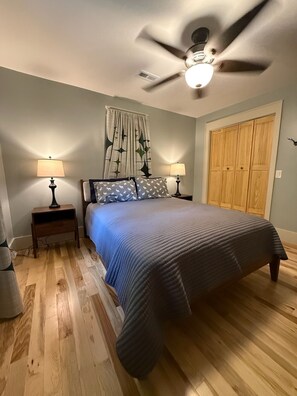 A bedroom with a bed, two bedside tables with lamps, a ceiling fan, a window with curtains, and a wooden wardrobe. - Highlands Mountain Hideaway. Views, Fireplace & Minutes to Downtown. (Highlands)