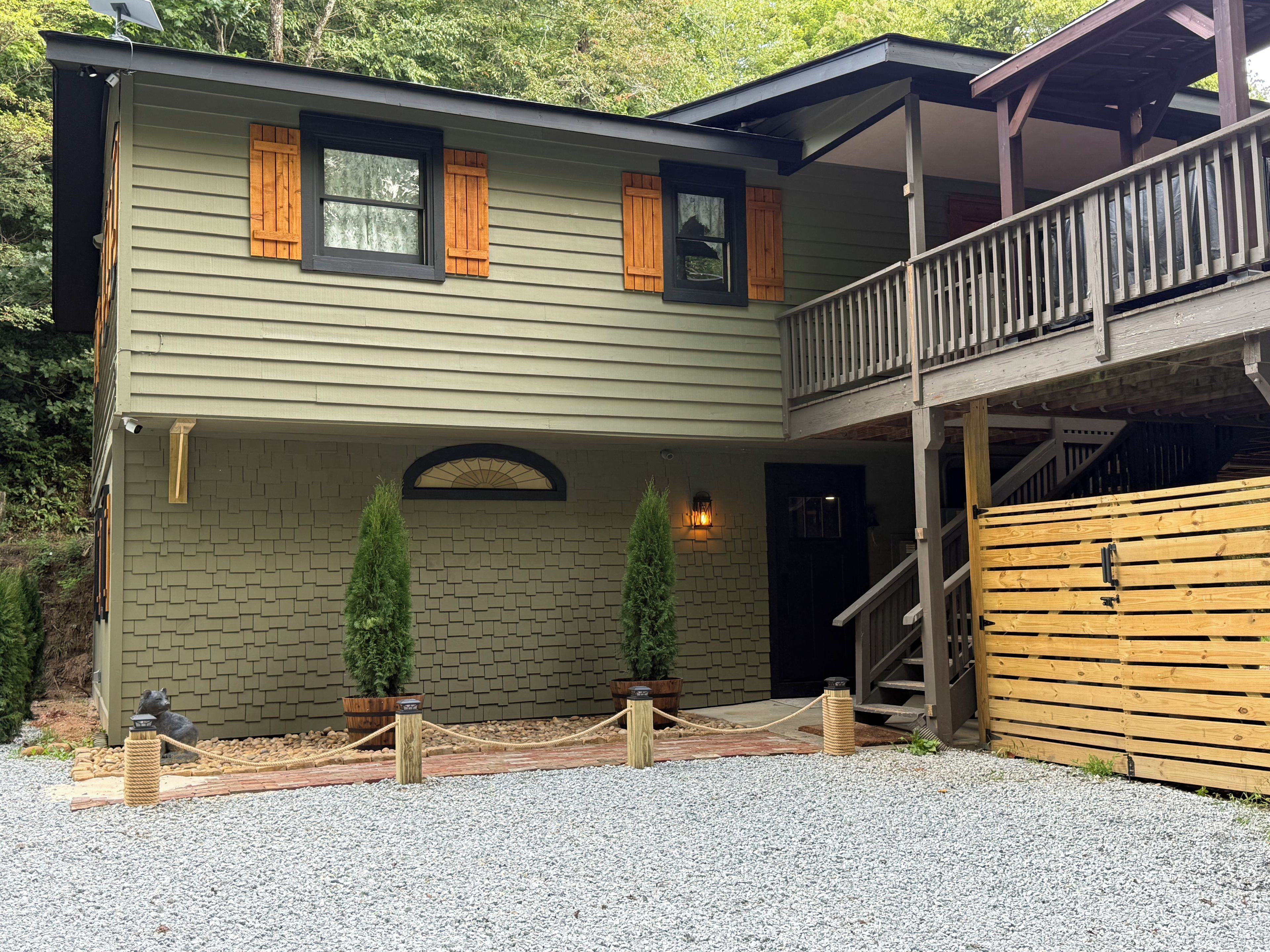 A two-story building with a balcony, a stone archway entrance, and a wooden fence.