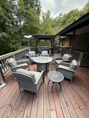 A deck with wicker furniture, a round table, and a grill. - Highlands Mountain Hideaway. Views, Fireplace & Minutes to Downtown. (Highlands)