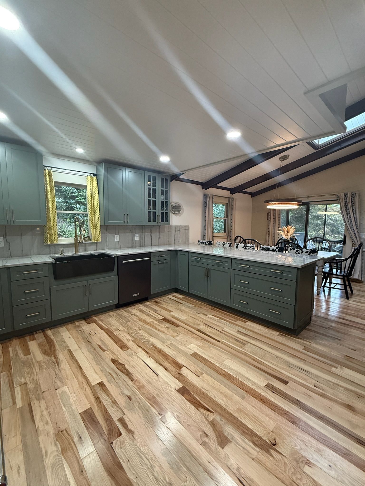 A modern kitchen with a large island, built-in cabinets, and a wooden floor.