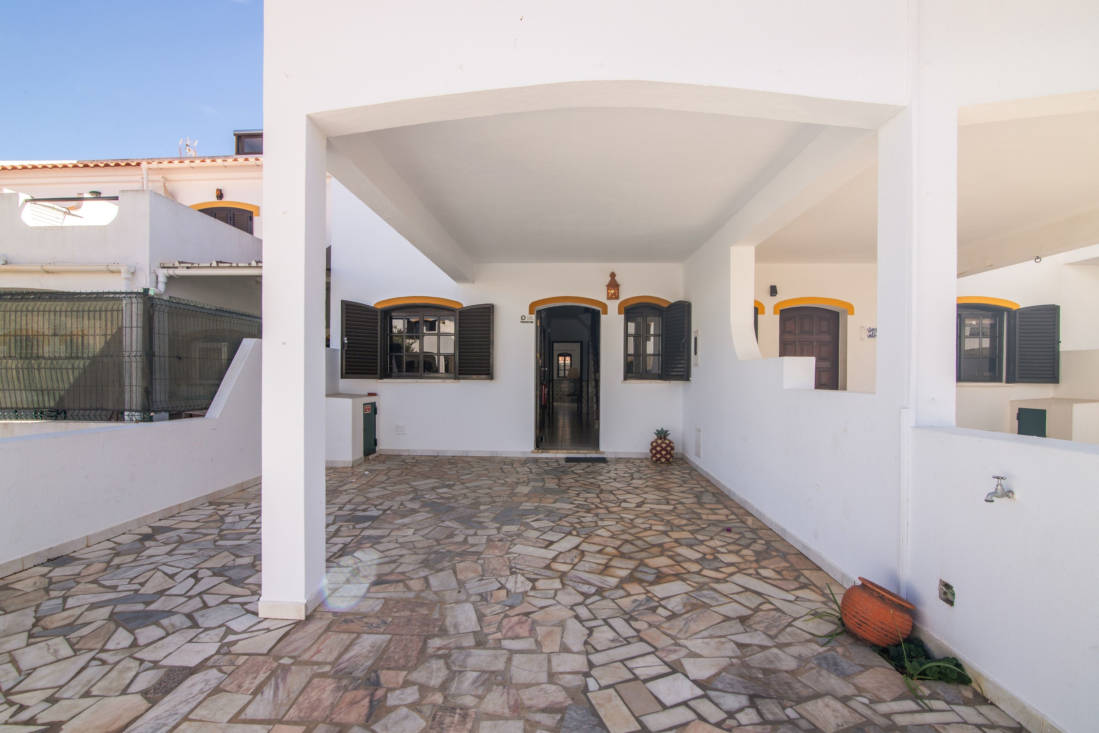 Un espacio al aire libre techado con piso de piedra, una puerta y una pequeña decoración de piña.