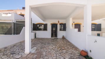 Un espacio al aire libre techado con piso de piedra, una puerta y una pequeña decoración de piña.