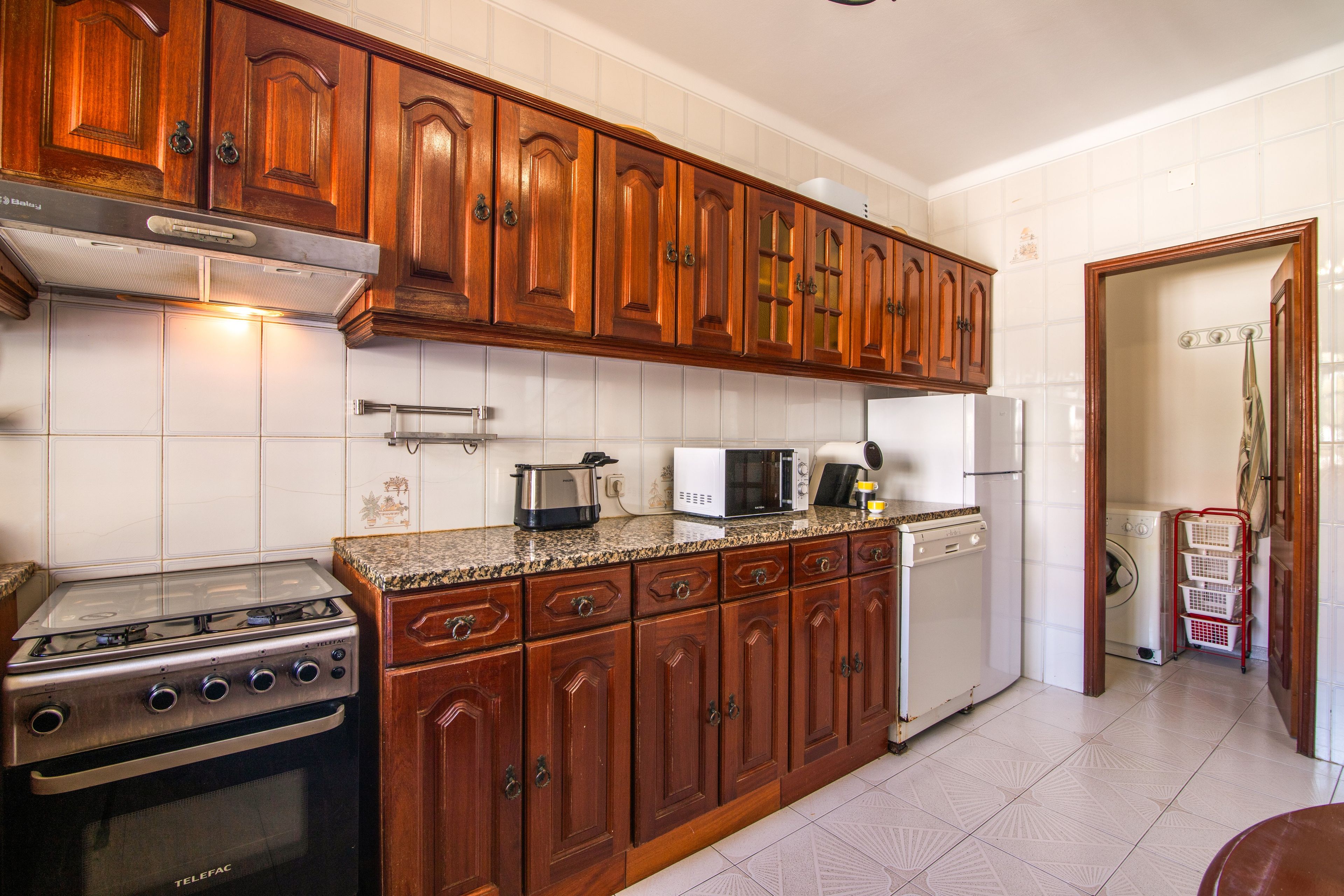 Una cocina con armarios de madera, estufa, microondas y lavavajillas.