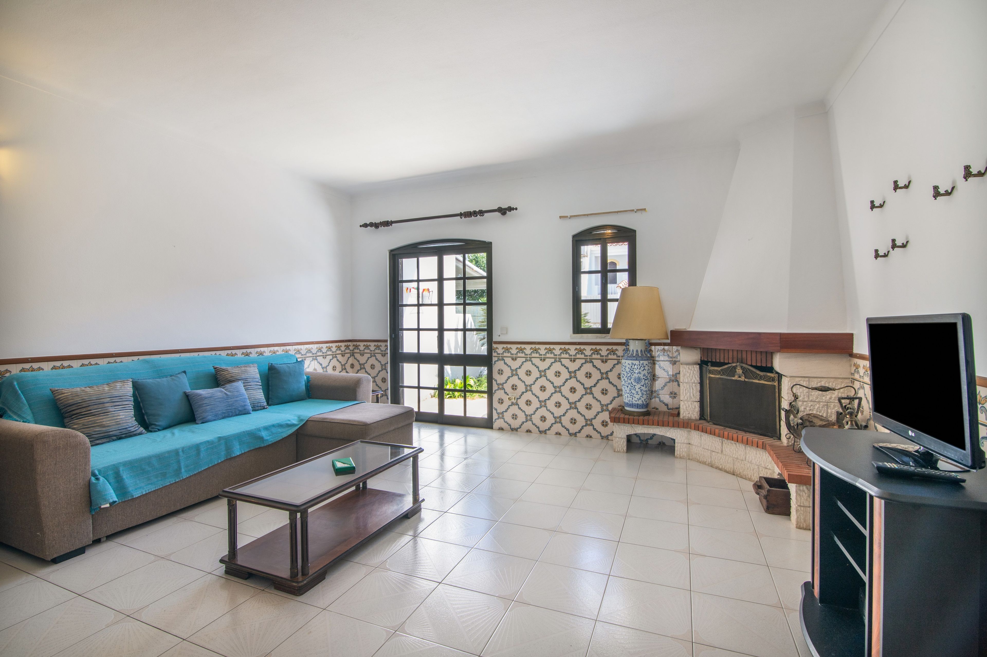 Una sala de estar con sofá, mesa de centro, televisor, chimenea y detalles decorativos en la pared.