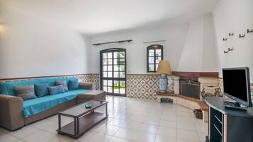 Una sala de estar con sofá, mesa de centro, televisor, chimenea y detalles decorativos en la pared.