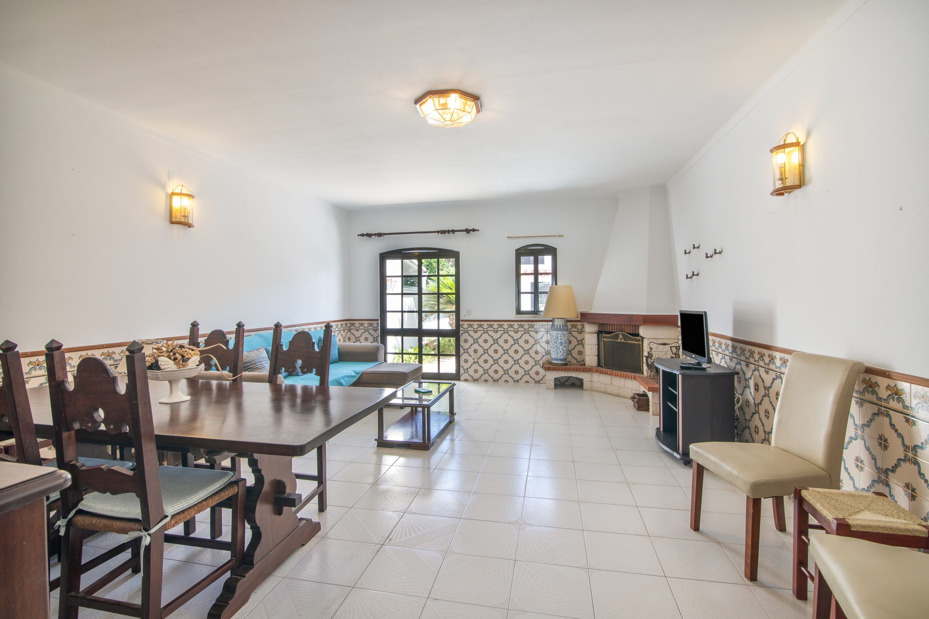 Amplia sala de estar con una mesa de comedor, sillas, un sofá y un televisor.