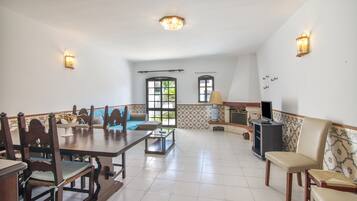 Amplia sala de estar con una mesa de comedor, sillas, un sofá y un televisor.