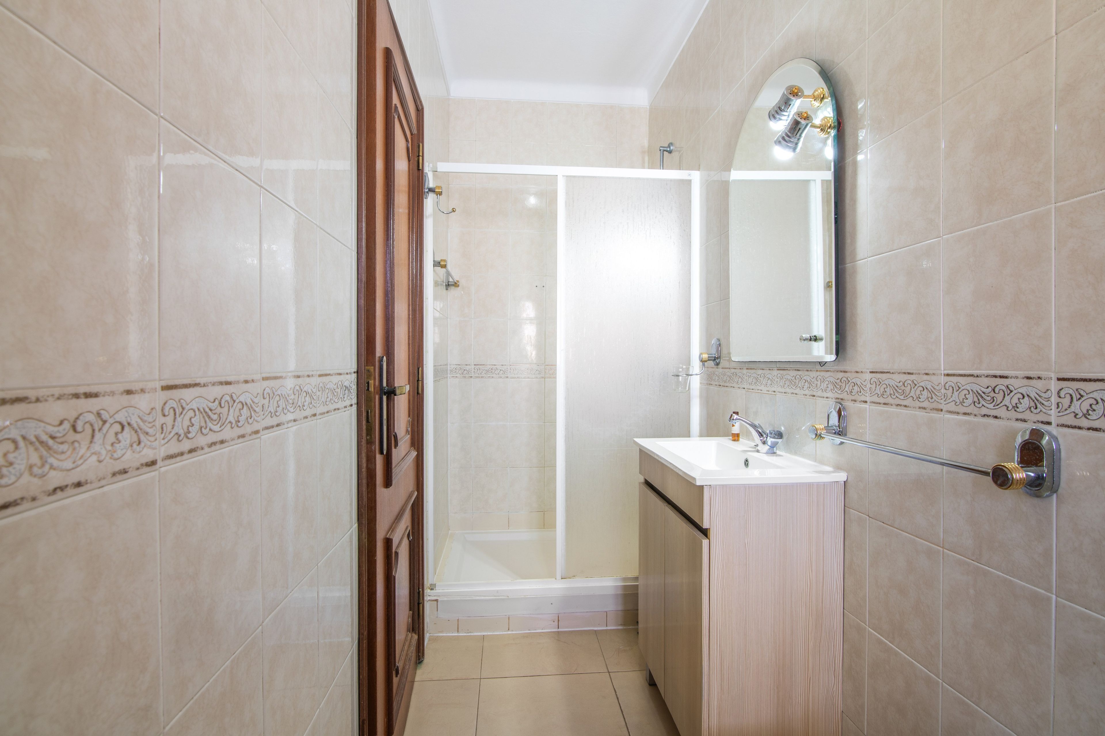 Une salle de bain avec une douche, un lavabo et un miroir.