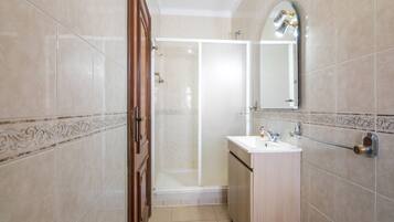 Une salle de bain avec une douche, un lavabo et un miroir.