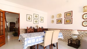 Un comedor con una mesa dispuesta para cuatro, una pared estampada y varias obras de arte enmarcadas.